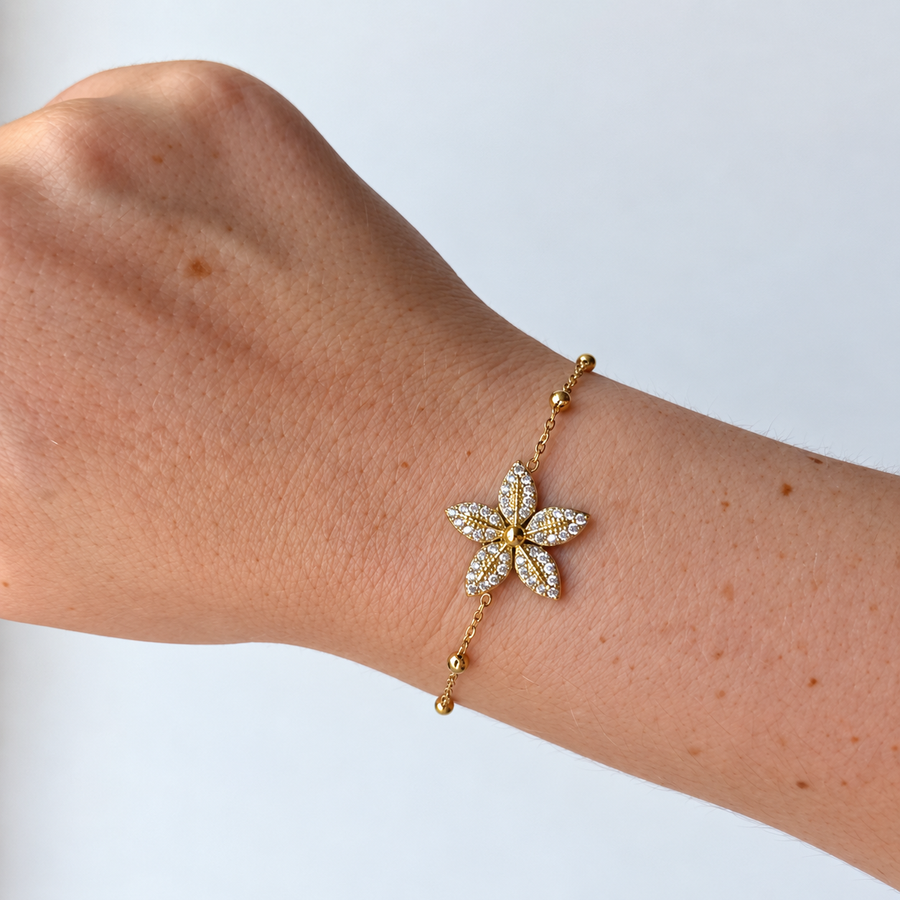 Armband met bloem en steentjes – goudkleurig gedragen aan de pols