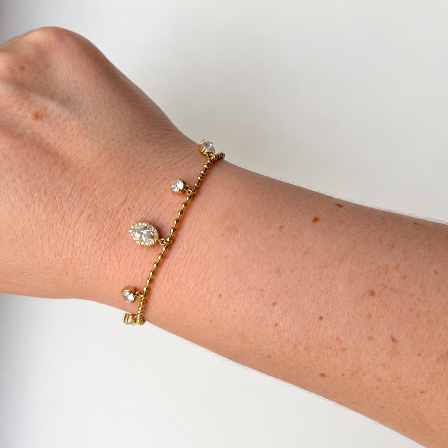 Armband met steentjes en ovale bedel – goudkleurig gedragen aan de pols