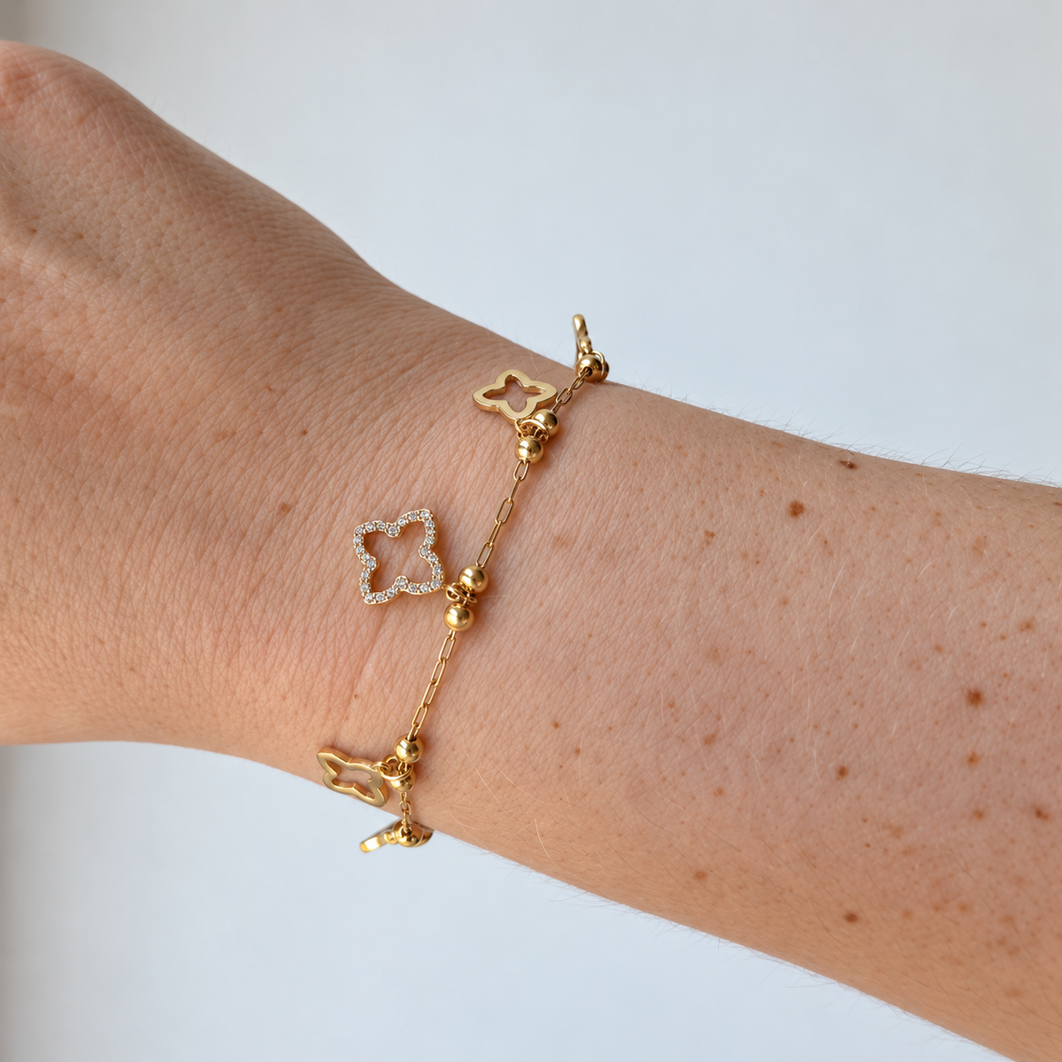 Armband met klaverbedels – goudkleurig gedragen aan de pols