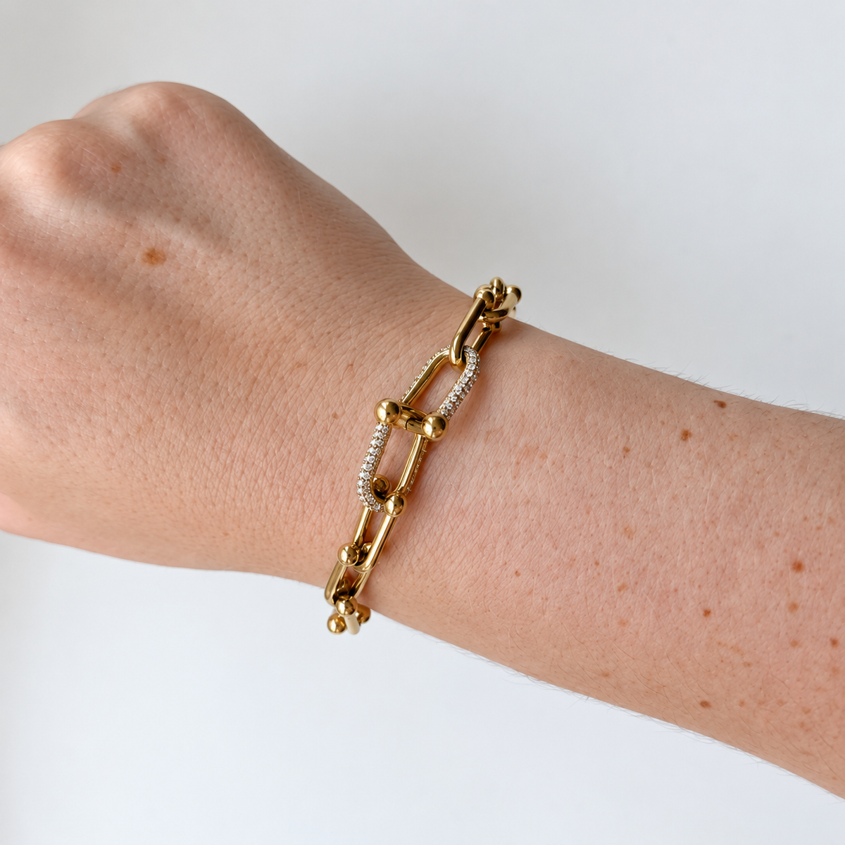Armband met langwerpige schakels en steentjes – goudkleurig gedragen aan de pols