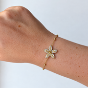 Armband met bloem en steentjes – goudkleurig gedragen aan de pols
