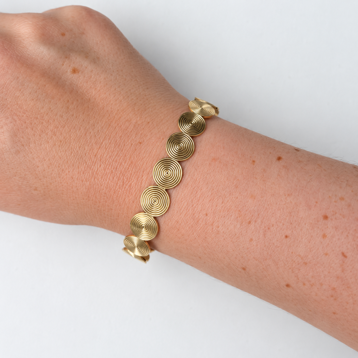 Armband met ronde spiraaldetails – goudkleurig gedragen aan de pols
