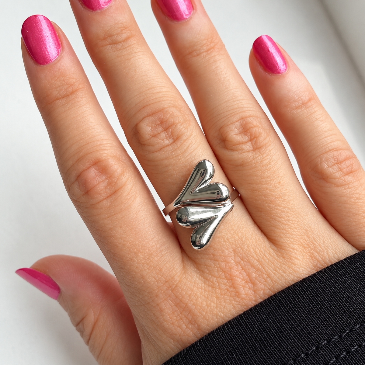 Zilverkleurige ring met twee harten gedragen aan de hand