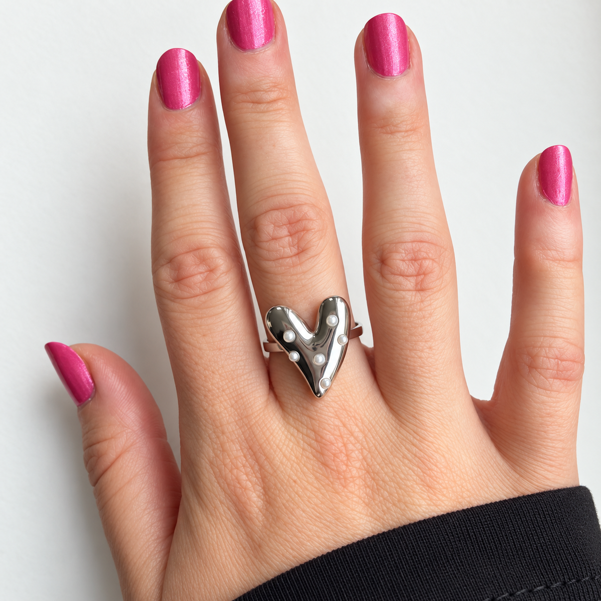 Zilverkleurige verstelbare ring met hart en zes pareldetails gedragen aan de hand