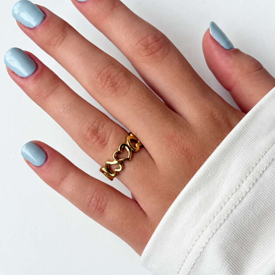 Goudkleurige ring met open hartjes gedragen aan de hand